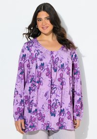 Lila Blumen-Tunika mit langen Ärmeln, ausgestattet mit verschiedenen Schattierungen von rosa und türkisfarbenen Blumen, plissiertem Design, weichem Stoff und rundem Ausschnitt.