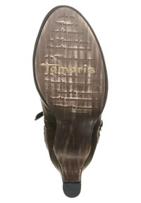 Braune Schuhsohle mit "Tamaris"-Markierung, ausgestattet mit einer strukturierten Oberfläche und verschiedenen Rillen für besseren Halt. Hergestellt aus Gummi.