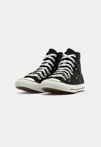 Zwarte high-top sneakers met witte veters, voorzien van een bloemenpatroon in verschillende kleuren aan de zijkanten en een rubberen zool met een gestructureerde grip.