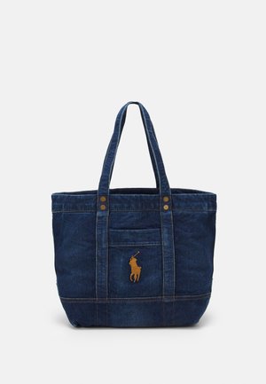Torba typu tote z ciemnoniebieskiego denimu z dwoma paskami na ramię oraz brązowym haftowanym logo gracza polo na przedniej kieszeni.