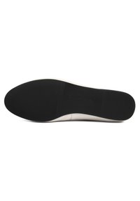 Sole boty s hladkým, zaobleným tvarem. Béžový a černý gumový materiál s horizontálními drážkami pro lepší úchop, minimalistický design.