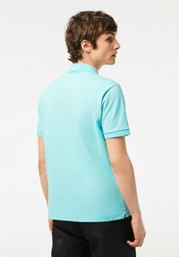 Polo a maniche corte di colore azzurro. Presenta un colletto classico, un tessuto testurizzato e dettagli delle cuciture sottili. Design pulito e minimalista.