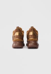 Καφέ αθλητικά παπούτσια με υφασμάτινη επάνω επιφάνεια με υφή, αντίθετες χρυσές λεπτομέρειες και παχύ καουτσούκ πάτο. Διαθέτει λογότυπα στις ταμπέλες της φτέρνας.