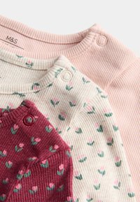 Drei langärmelige Oberteile aus weichem Baumwollstoff: eines in zartem Rosa, eines in Creme mit pinkem Blumendesign und eines in Burgunderrot mit einem ähnlichen Blumenmuster.