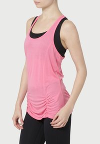 Różowy sportowy top na ramiączkach z dekoltem w kształcie łódki, marszczeniem po bokach oraz czarną warstwą pod spodem. Wykonany z lekkiego materiału.