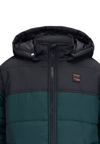 Giacca imbottita con un design a blocchi di colore nero e verde. Presenta una chiusura con zip sul frontale e un cappuccio, con una patch del logo sul petto.