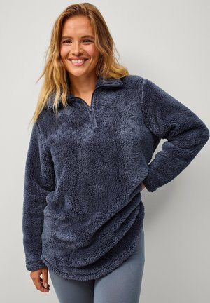 Mørkeblå fleece-pullover med halv lynlås, høj krave og tekstureret, blød stof. Har løs pasform og afrundet kant.