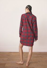 Košeľové šaty so vzorom červeného a zeleného káro, s dlhými rukávmi, zapínaním na gombíky vpredu, zaobleným lemom, vyrobené z jemnej tkaniny, so voľným strihom a detailom zadného sedla.