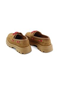 Zapatos de slip-on de material marrón y suave con una suela de goma gruesa. Detalles en rojo y blanco en los cordones y las costuras. Diseño grueso y texturizado.