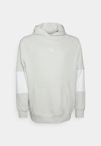 Sudadera gris claro con paneles de manga blanca, bolsillo canguro frontal y pequeño logotipo "cK" en blanco impreso en el pecho.
