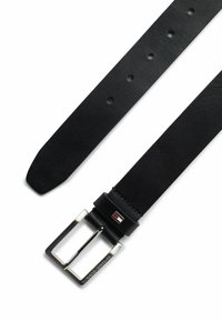 Cintura in pelle nera con una texture liscia, fibbia in argento e un piccolo dettaglio del logo. Presenta diversi fori per una dimensione regolabile.