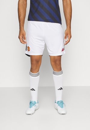 Weiße Fußballshorts mit schwarzen Akzenten und dem Manchester United-Logo, kombiniert mit weißen Socken mit schwarzen Streifen und hellblauen Fußballschuhen.