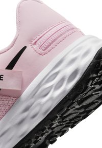 Bottines de sport roses avec un dessus lisse, un panneau en maille texturée et une semelle ondulée blanche. Présente un logo noir et une semelle en caoutchouc noir solide.