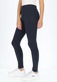 Marineblauwe geribbelde legging met een hoge taille en een gladde textuur, gecombineerd met witte platform sneakers met een logo aan de zijkant.