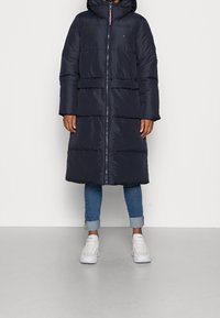 Námořnická prošívaná bunda s kapucí, zapínáním na zip a dvěma vodorovnými předními kapsami. Má prošívaný design s prošitými částmi.