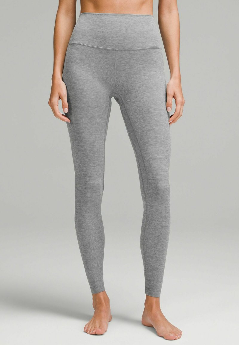 Leggings alti grigi realizzati in un materiale morbido e elastico. Presentano una silhouette aderente e una superficie liscia senza cuciture visibili.