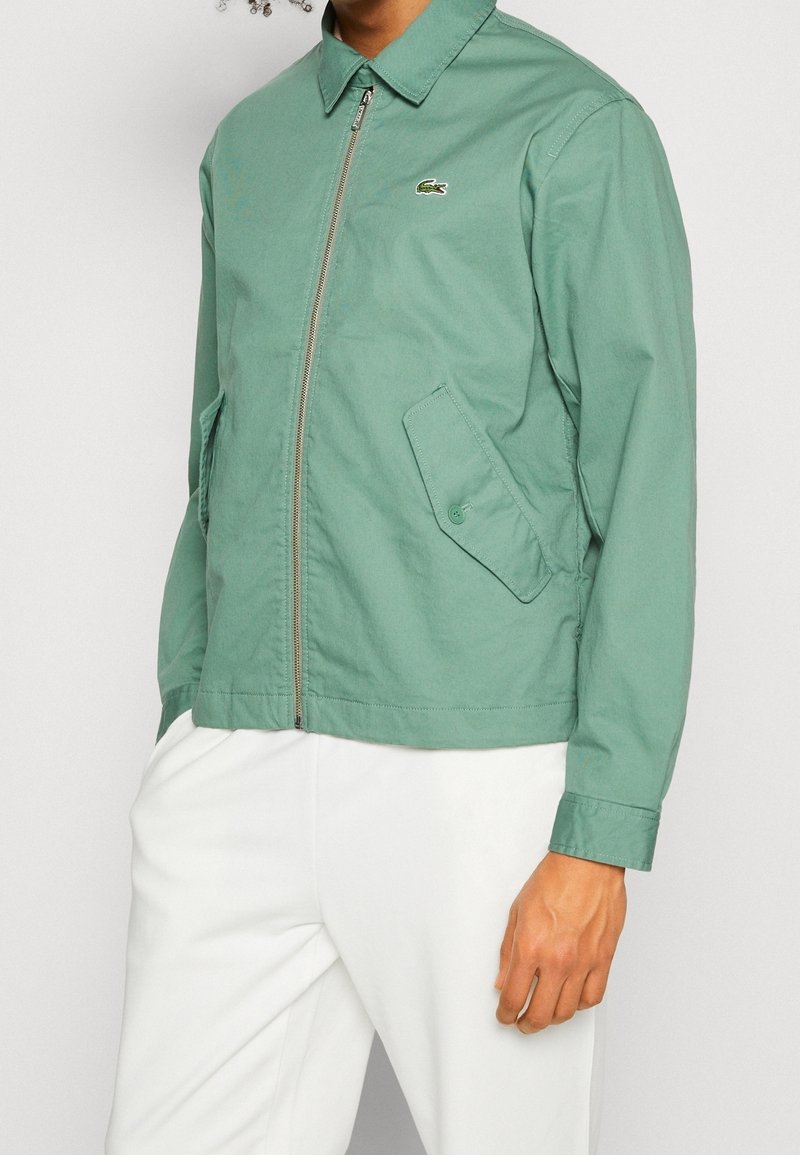 Veste vert clair zippée avec col, deux poches avant et un petit logo sur la poitrine. Confectionnée dans un tissu lisse avec une coupe décontractée.