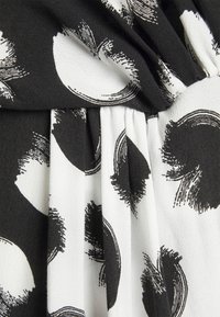 Czarnobiały materiał z teksturowanym wzorem składającym się z abstrakcyjnych pociągnięć pędzla i okrągłych kształtów, z detalem w postaci zgromadzonych fałd.