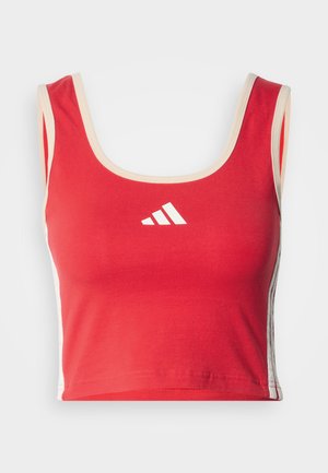 Red crop top with a scoop neck, beige trim, and white logo. Features white vertical stripes on the sides. Made from soft, stretchy fabric.