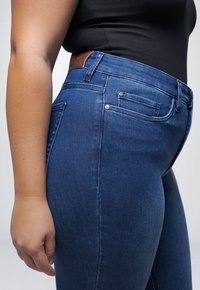 Donkerblauwe spijkerbroek met een slim fit ontwerp. Kenmerken zijn onder andere vijf zakken, zilverkleurige hardware en een leren label op de taille.