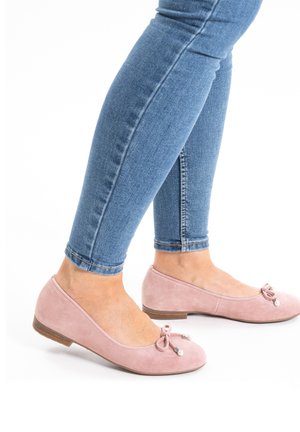 Rosa Wildlederballerinas mit runder Zehenpartie, die eine kleine Schleife und dekorative Perlen besitzen. Die Sohle ist flach mit einem leichten Absatz und wird mit blauen Skinny-Jeans kombiniert.