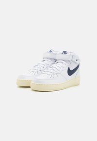 Hvite lær høy-typer joggesko med en marineblå Swoosh og akcentuer, med perforert tå og Borrelås ankelstropp. Kremfarget gummisåle.