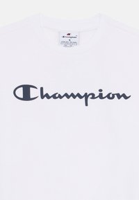 Hvit bomull t-skjorte med en stor marinebl�å "Champion" logo i kursiv på forsiden. Klassisk crew neck-design, glatt tekstur.