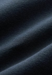 Dark navy fabric with a soft texture, featuring a fine knit pattern that creates subtle waves and depth.