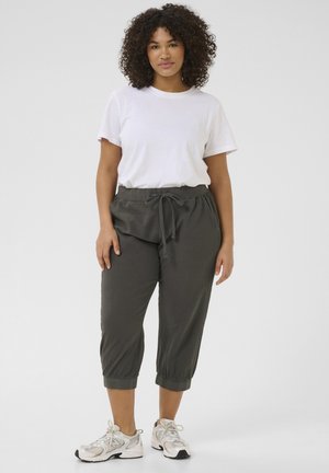 Opuste hlače od džersija u tamno sivoj boji s elastičnim pojasom, užeom za podešavanje i skraćenom dužinom. Uparene s jednostavnom bijelom majicom.