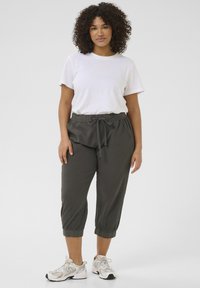Pantaloni jogger con vestibilità rilassata in grigio scuro, con vita elastica, cordino e lunghezza cropped. Abbinate a una maglietta bianca semplice.