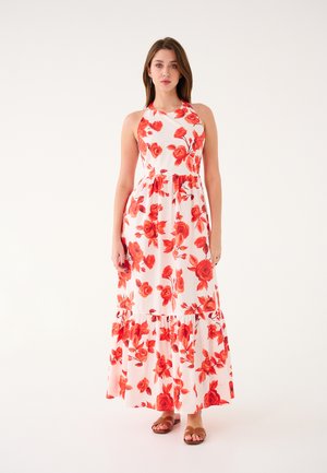 Robe maxi florale blanche avec des motifs de roses rouges, présentant un design à col halter et un ourlet à volants en couches. Le tissu semble léger et fluide.