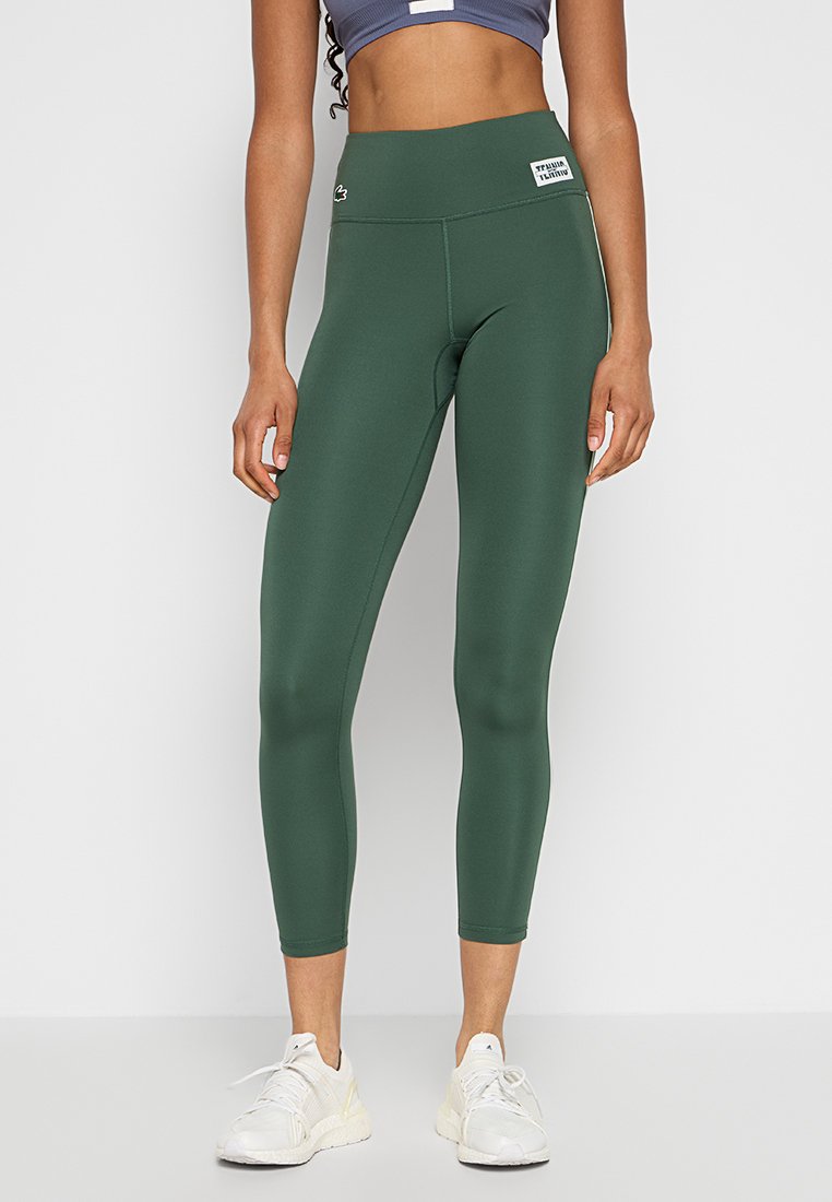 Leggings sportivi verdi realizzati in un tessuto morbido e elasticizzato, con un'alta vita e un dettaglio con il logo sulla parte anteriore.