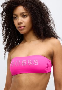 Ροζ τοπ bandeau με γράμματα από στρας που σχηματίζουν τη λέξη "GUESS", με ομαλή υφή και εφαρμοστό σχέδιο, κατάλληλο για μαγιό.