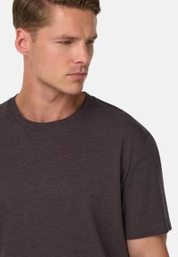 Tamsiai pilka crew tipo marškinėliai, pagaminti iš švelnios medžiagos, su trumpomis rankovėmis ir laisvu siluetu, o kaklo iškirpimas lengvai riebokas.