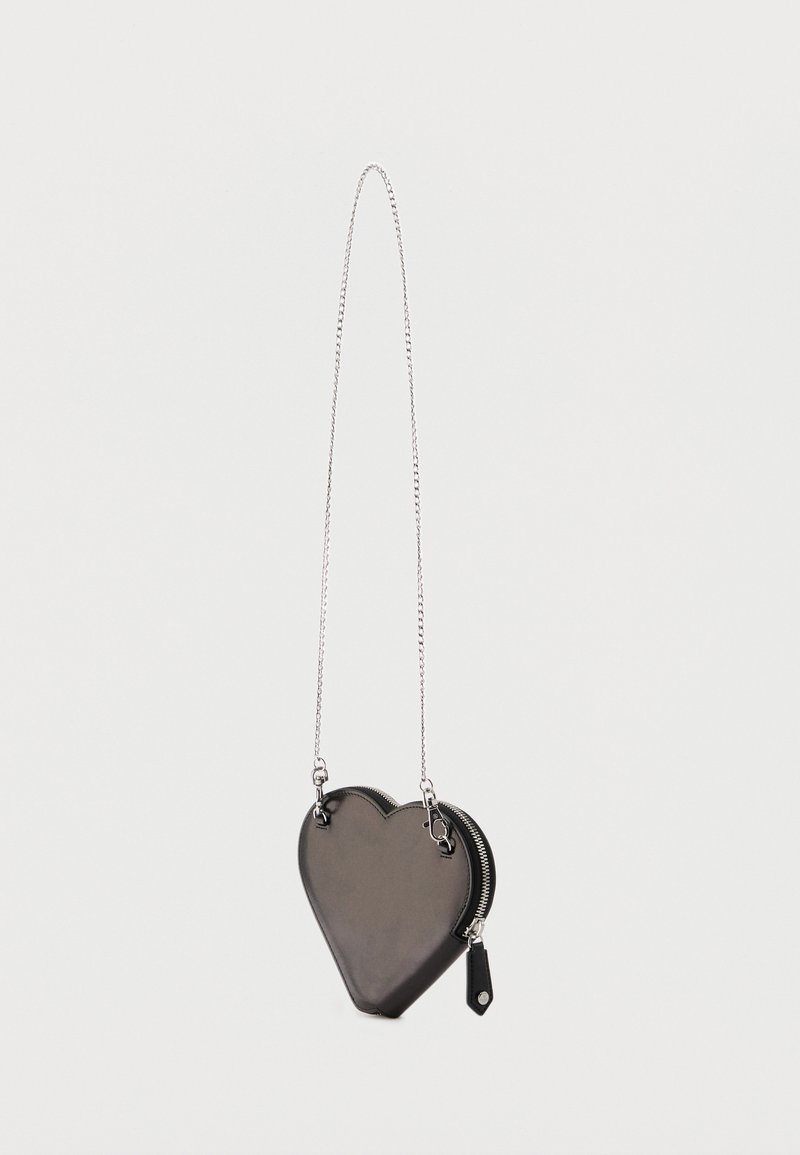 Borsa nera a forma di cuore con cerniera e lunga tracolla a catena argento appesa su sfondo bianco.
