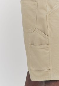 Khaki cargo shorts made of durable fabric, featuring multiple pockets, a relaxed fit, and stitched seams for added strength.