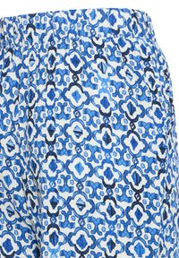 Tissu à taille élastique bleu et blanc avec un motif géométrique répétitif évoquant des carreaux ou des quadrilobes.