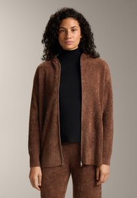 Hnedý kardigán na zips vyrobený z mäkkého pleteného materiálu, s kapucňou a rebrovanými manžetami, doplnený čiernym rolákom pod ním.