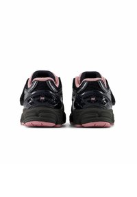Des baskets noires et roses avec une tige en maille, un collier rembourré et une sangle réglable. Elles présentent un talon texturé et une semelle contrastante.