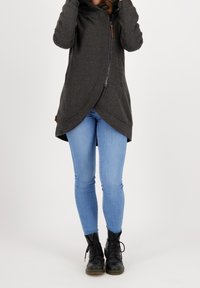 Szara kurtka z kapturem na zamek z asymetrycznym dołem i dwoma kieszeniami. Nosi się ją na jasnoniebieskie dżinsy i czarne, sznurowane buty. Miękki, teksturowany materiał.