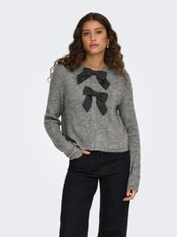 Gray knit sweater with long sleeves, featuring two black satin bows at the neckline. Worn with black pants, showcasing a relaxed fit.