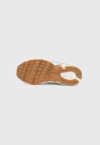 Semelle de chaussure de sport, présentant une semelle extérieure en caoutchouc brun avec des motifs de grip texturés, une semelle intermédiaire blanche et des accents gris sur le dessus. Design flexible et robuste.