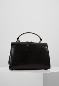 Svart läderhandväska med texturerad yta, strukturerad form, topphandtag och detaljer i guldfärg. Har ett spänne för stängning.