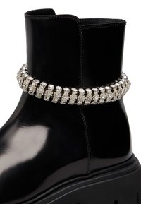 Stivale alla caviglia in pelle nera con suola spessa e una fascia decorativa attorno alla caviglia ricoperta di scintillanti strass.