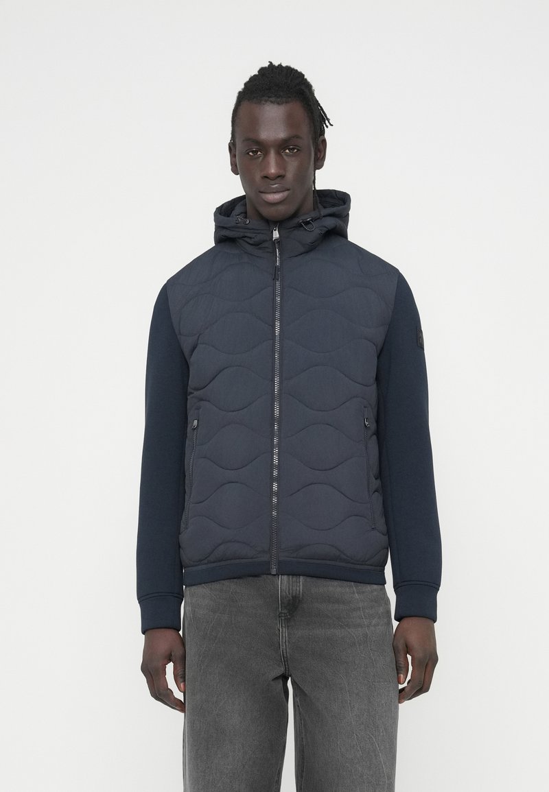 Μπλε ναυτικό καπιτονέ μπουφάν με φερμουάρ μπροστά, κουκούλα και ριμπ μανσέτες. Διαθέτει λείο ύφασμα και δίχρωμο σχέδιο με υφασματικό μοτίβο.