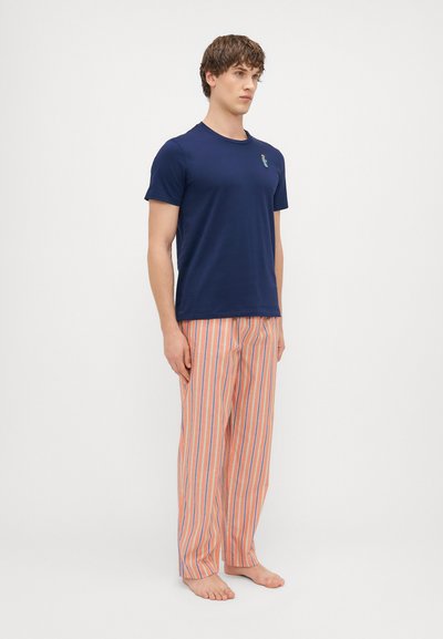 Tamno plava majica kratkih rukava s malim crtežom; narančasto-plave prugaste široke pidžama hlače; mekani materijal; bosa stopala.