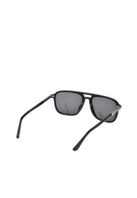 Lunettes de soleil rectangulaires noires avec verres teintés foncés et branches fines, vues de dos sur fond blanc.