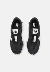 Baskets de sport noires avec une tige en mesh, accents blancs et une semelle sombre. Présentent un design traditionnel à lacets et un logo en relief.
