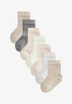 Set van acht geribbelde sokken in verschillende neutrale kleuren: beige, grijs, gebroken wit en lichtroze. Elke sok heeft een zachte, gestructureerde brei-design.
