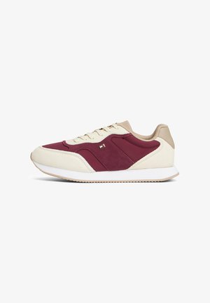 Sneakers z kremową cholewką, burgundowymi akcentami z zamszu, beżowymi detalami, białą podeszwą i małym logo po bocznej stronie.